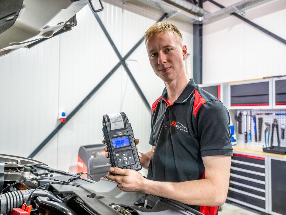 Monteur van FZ Auto's laat de accutester zien na het doormeten van de accu in Peize