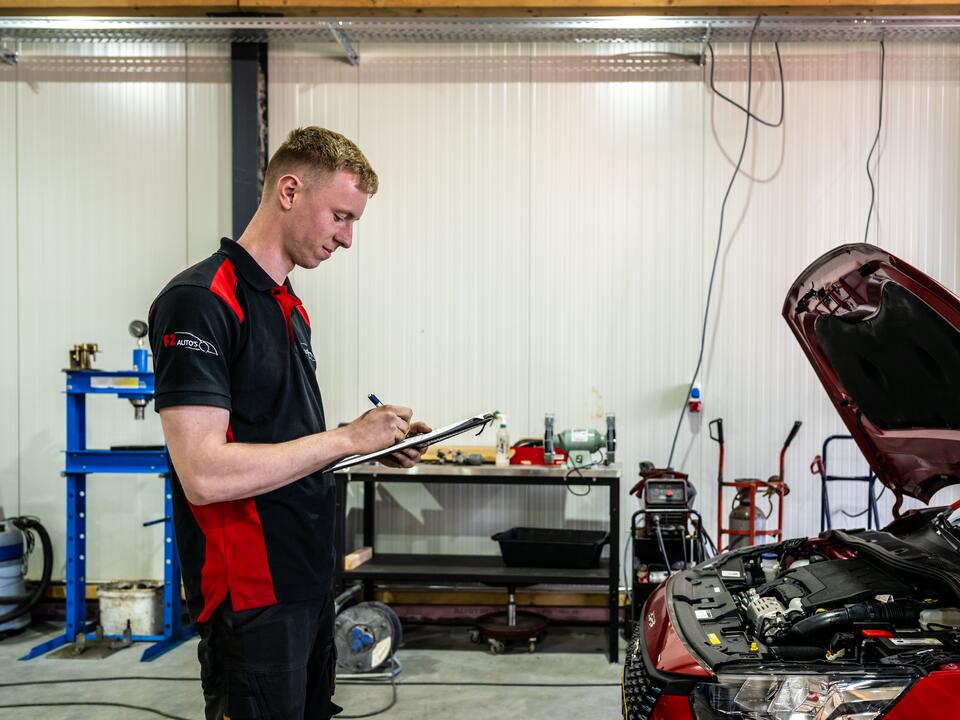 Monteur van FZ Auto's vult het keuringsrapport in op het klembord in de werkplaats in Peize