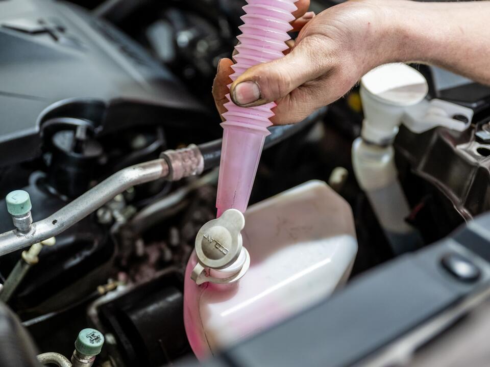 Koelvloeistof wordt bijgevuld in het expansievat bij FZ Auto's in Peize