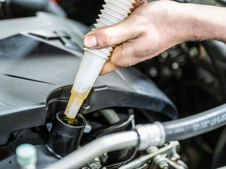 Motorolie wordt via een trechter bijgevuld in de werkplaats van FZ Auto's