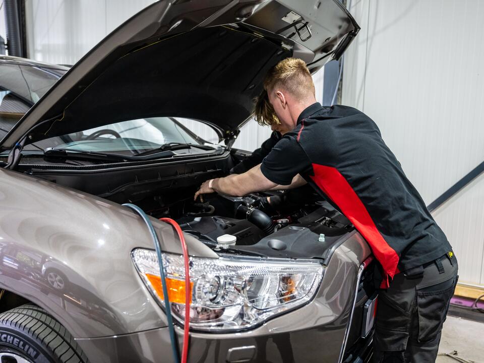 Monteur van FZ Auto's buigt diep over de motorruimte tijdens een onderhoudsbeurt