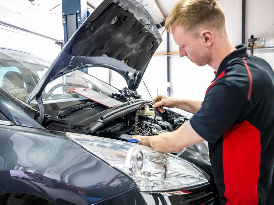 Monteur van FZ Auto's werkt in de motorruimte van een auto in Peize
